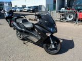 une moto noire garée sur un parking près d'une clôture