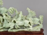 a statue of a group of horses running on a wooden base
