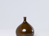 un petit vase brun posé sur une surface blanche