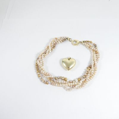 bracelet de perles orné d'un pendentif en forme de cœur doré sur fond blanc