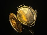 a close up of a gold pocket watch on a black surface