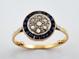 gros plan d'une bague en or avec des pierres bleues et blanches