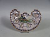 une petite assiette ornée d'un oiseau, posée sur un socle