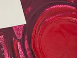 someone is painting on a piece of paper with red paint
