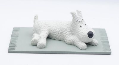 une figurine de chien blanc posée sur un tapis