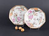 deux assiettes ornées de fleurs et de noix, posées sur un fond noir