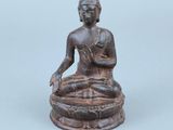 une ancienne statue en bronze représentant une personne assise en position du lotus