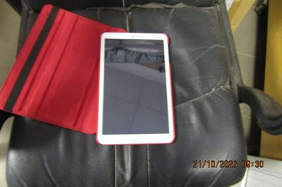 une tablette posée sur un fauteuil en cuir noir recouvert d'une housse rouge