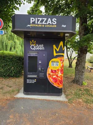 un distributeur automatique sur lequel est posée une pizza, dans un parc