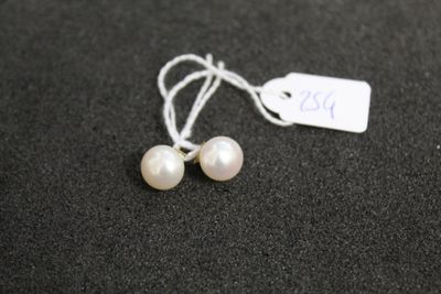 une paire de boucles d'oreilles en perles blanches avec une étiquette de prix sur un fond noir