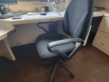 a desk with a computer and a chair in front of a window