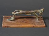 bronze statue of a cat on a wooden base on a black background