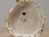 a close up of a small white vase on a table