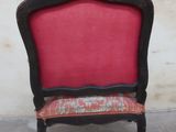 a red and black chair with a red cushion in front of a white wall