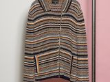 a sweater hanging on a rack in front of a pink wall
