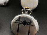 two silver pocket watches are sitting next to each other on a black surface