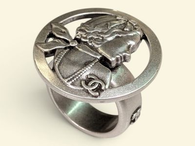un gros plan d'une bague en argent sur laquelle est gravé le visage d'une femme