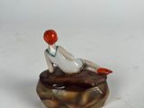 a figurine of a woman sitting on a rock