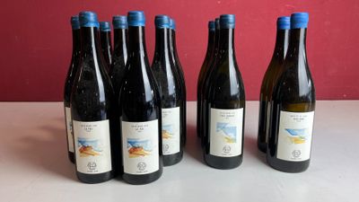 six bouteilles de vin sont posées sur une table devant un mur rouge