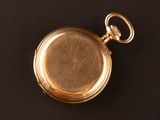 an old gold pocket watch with a chain on a black surface