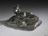 statue d'un chat allongé sur un rocher, posée sur un fond blanc
