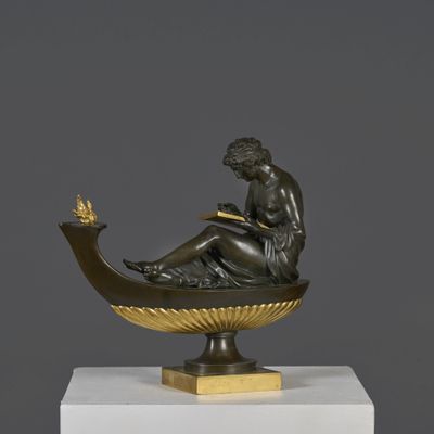 sculpture en bronze représentant une femme assise sur un bateau, tenant un oiseau dans la main