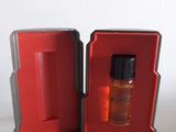 une boîte rouge contenant un petit flacon de parfum