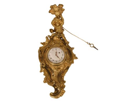 a gold clock hanging from the side of a wall
