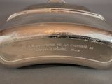an old silver plate with a silver lid on a table