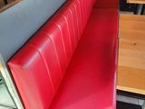un banc rouge dans un restaurant avec une table et des chaises en bois