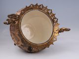 a gold vase with a handle on a white table