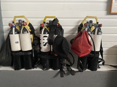 Plusieurs équipements de plongée sont alignés sur une étagère dans un garage