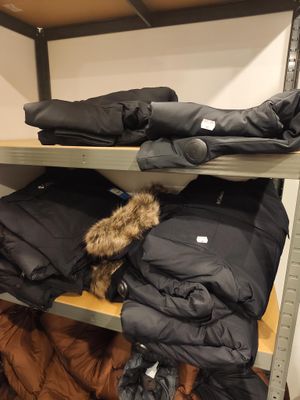 Plusieurs manteaux et vestes sont empilés sur une étagère dans une pièce
