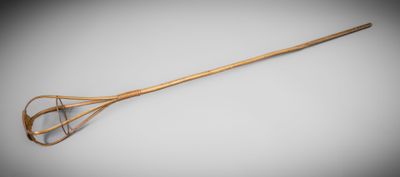 une cuillère en bois avec un manche, posée sur une surface grise