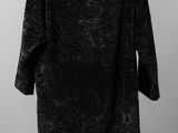 a black coat hanging on a hanger against a wall