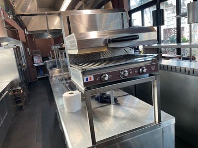 une cuisine professionnelle équipée de plans de travail en inox et d'un grand grill