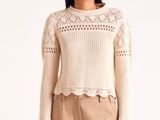 an image of a woman wearing a white sweater and tan pants