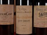 three bottles of red wine are lined up on a table