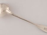 an antique silver spoon with a spoon handle on a white surface
