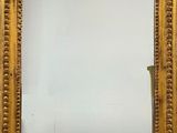 un miroir à cadre doré sur lequel est posé un bougeoir