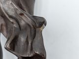 bronze statue of a woman holding a flower in her right hand