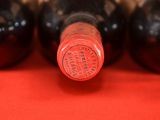 four bottles of wine are lined up on a red surface