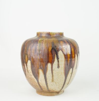 a brown and white vase sitting on a white surface