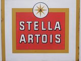 an old style stella artois sign hanging on the side of a building