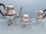trois théières en argent et une théière posées sur une table