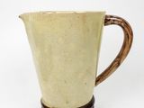 brown and white pitcher on wooden stand against white background