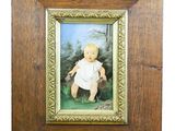 an old picture of a baby in a white dress in a wooden frame