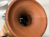 a person holding a brown vase with a black substance in it