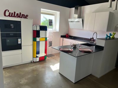 une cuisine blanche avec un plan de travail noir et un réfrigérateur coloré
