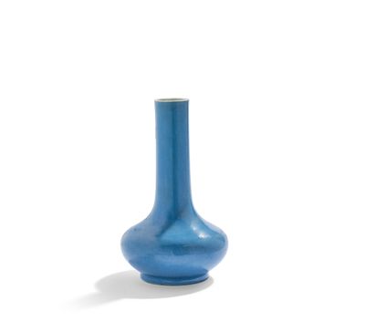 un vase bleu posé sur une surface blanche